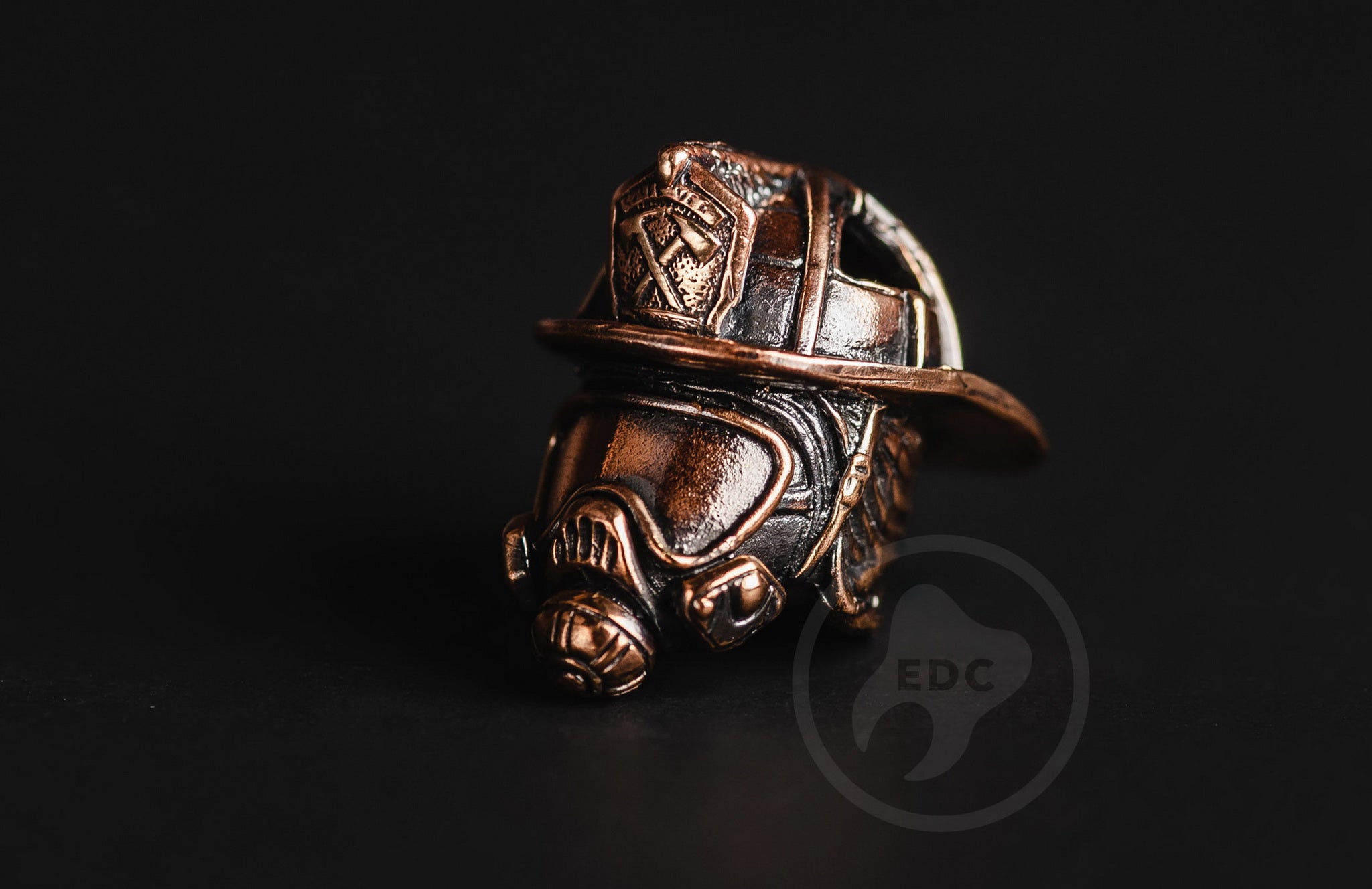 Side view of the brass Fire Chief helmet bead showing the ribbed dome and blackened finish.-2