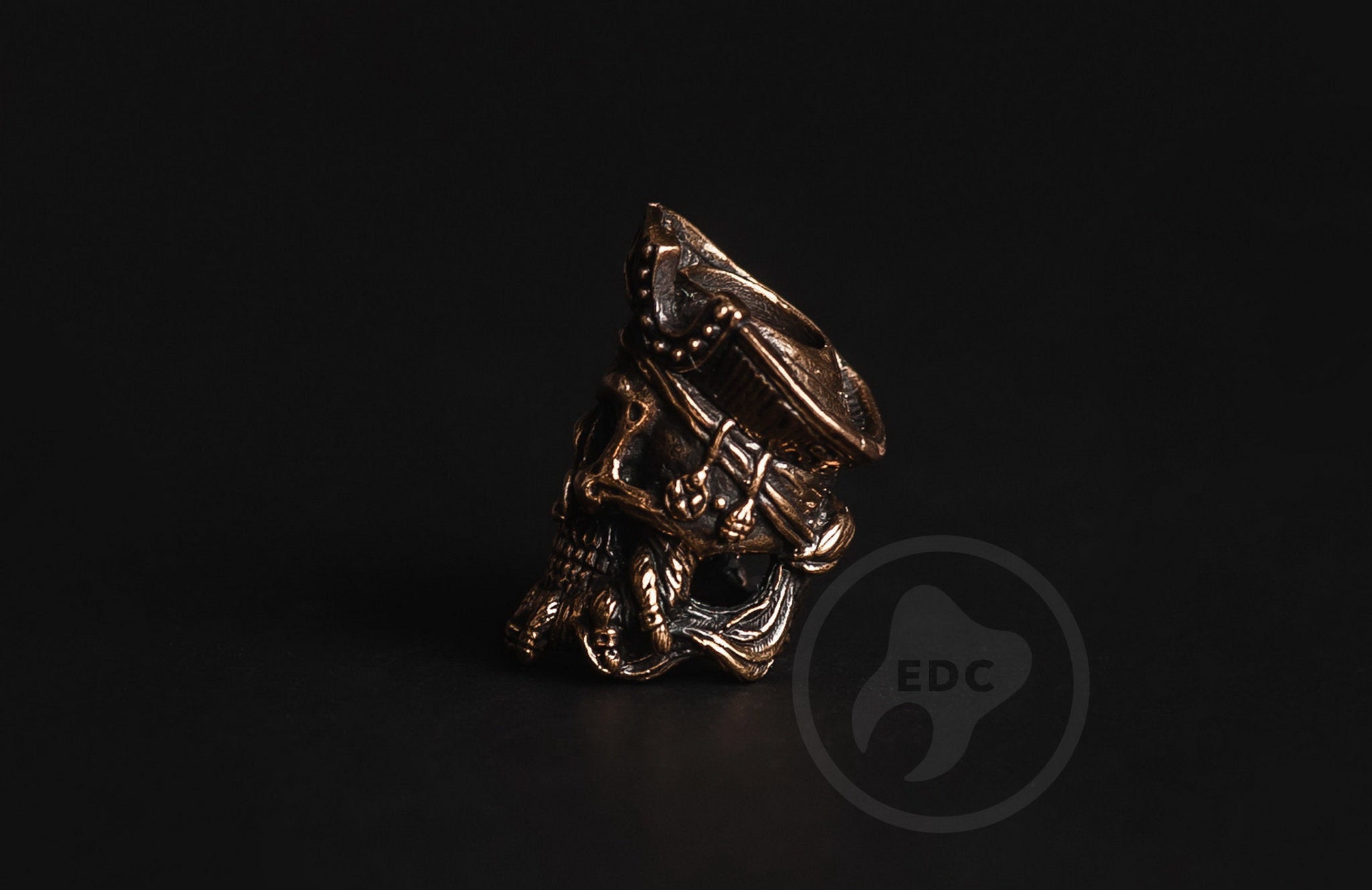 Profile view of the antique-finished brass pirate skull bead showing the 6mm lanyard hole.-1