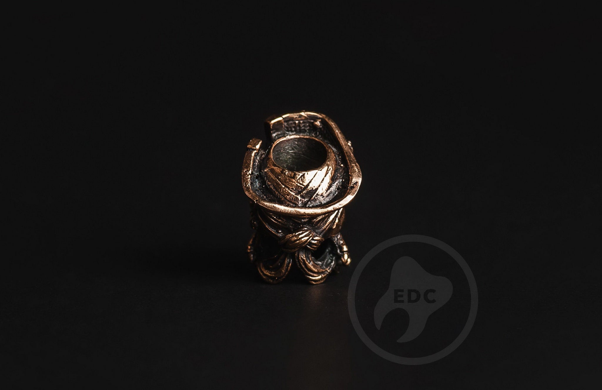 Profile view of the antique-finished brass pirate skull bead showing the 6mm lanyard hole.-2