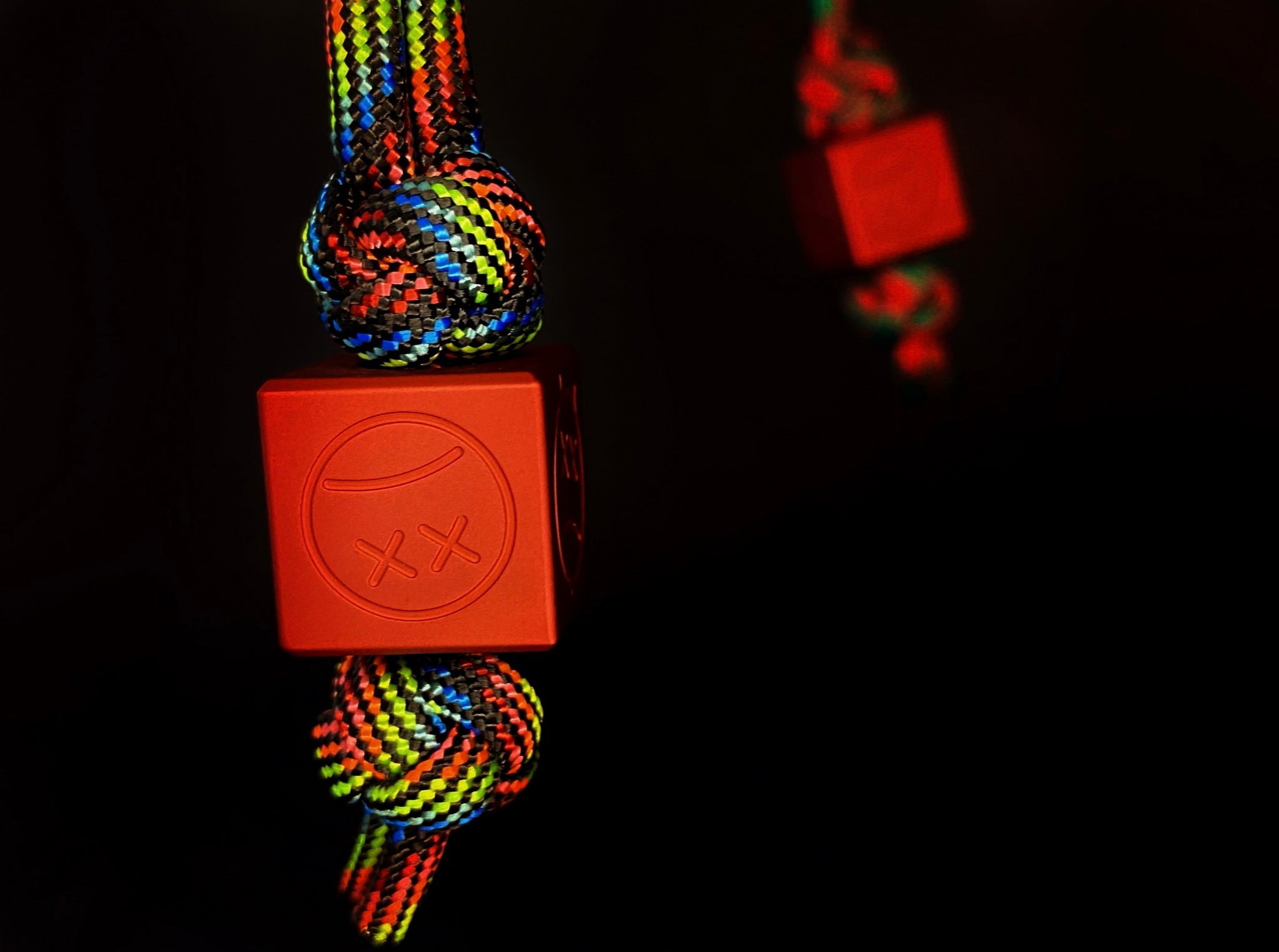 Matte red aluminum Sad Face bead showing the top 6mm lanyard hole.-1
