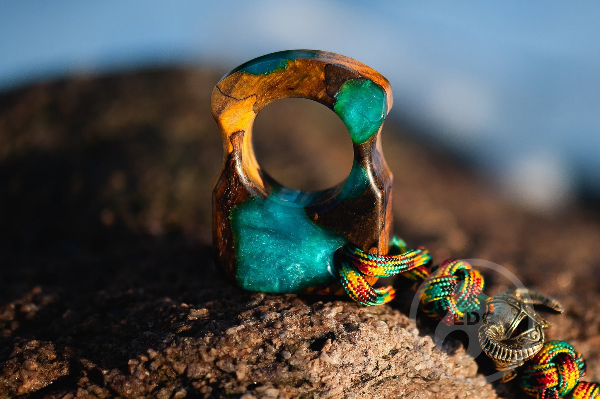 Close up of solid brass Dragonborn helmet bead on blue lanyard, Texture detail of ash suvel and blue resin nordic pocket sculpture
