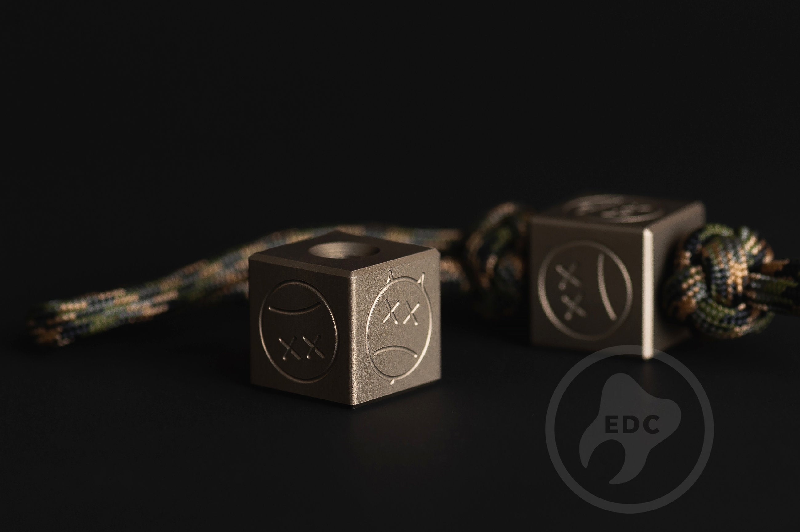 Dark hardcoat aluminum Sad Face bead showing precision machining.