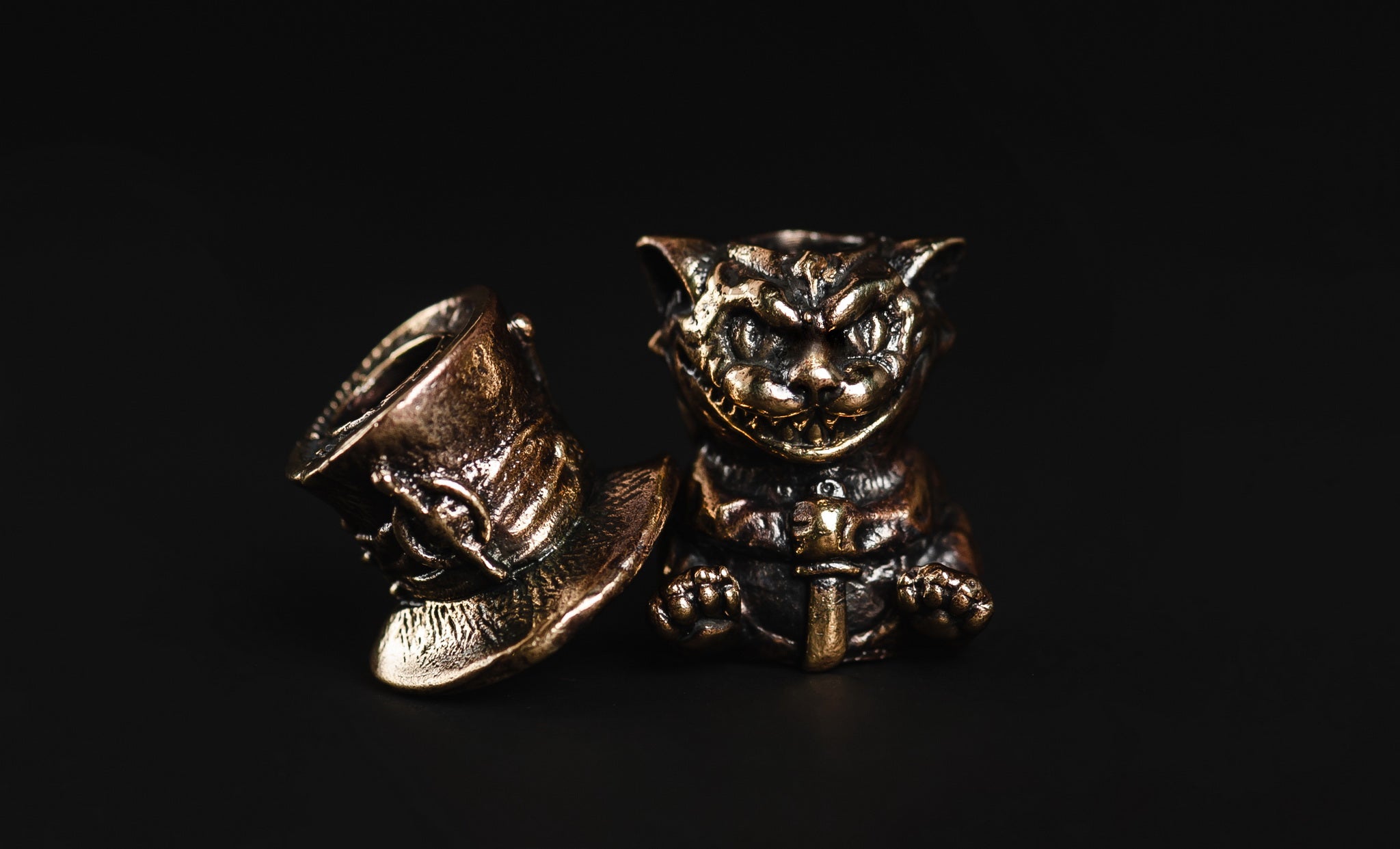 Close-up of the iconic grin and top hat on the solid brass Cheshire Cat bead.