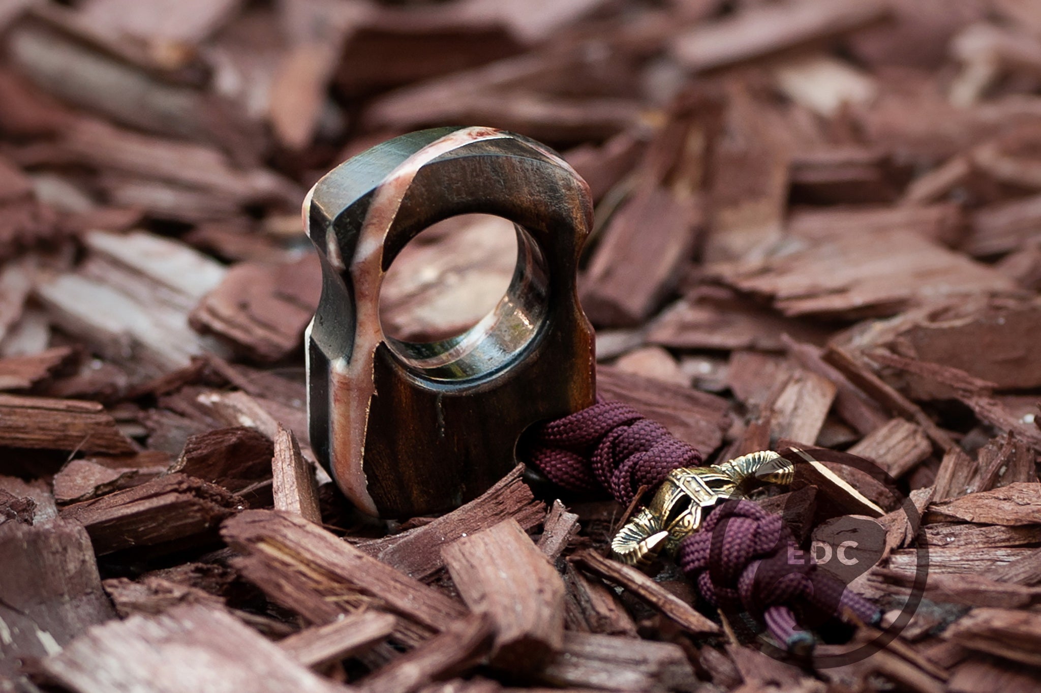 Close up of brass Dragonborn warrior bead on hybrid wood EDC tool, Texture detail of marble and snow resin effect on stabilized wood