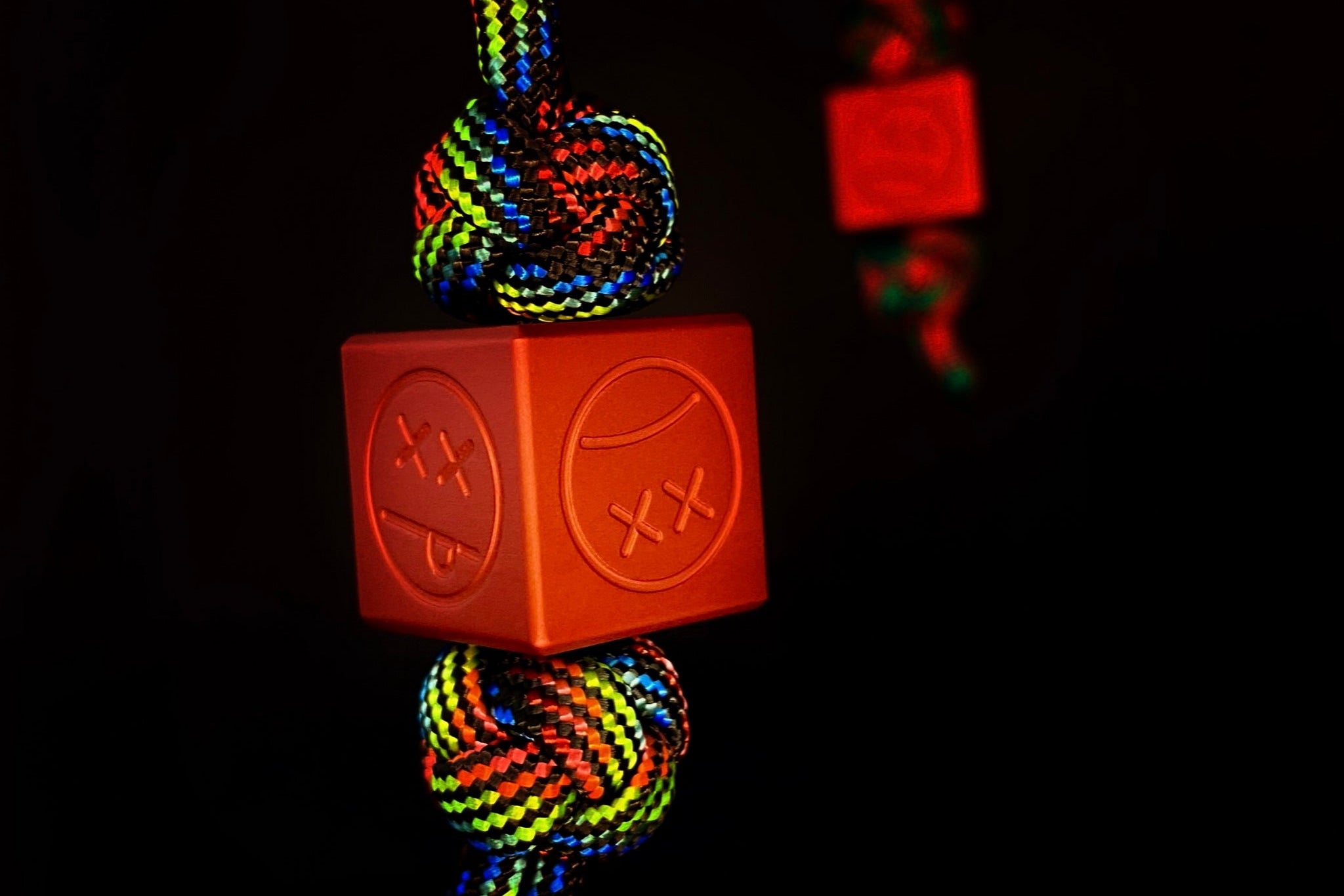 Sandblasted matte red aluminum Sad Face Cube EDC charm.