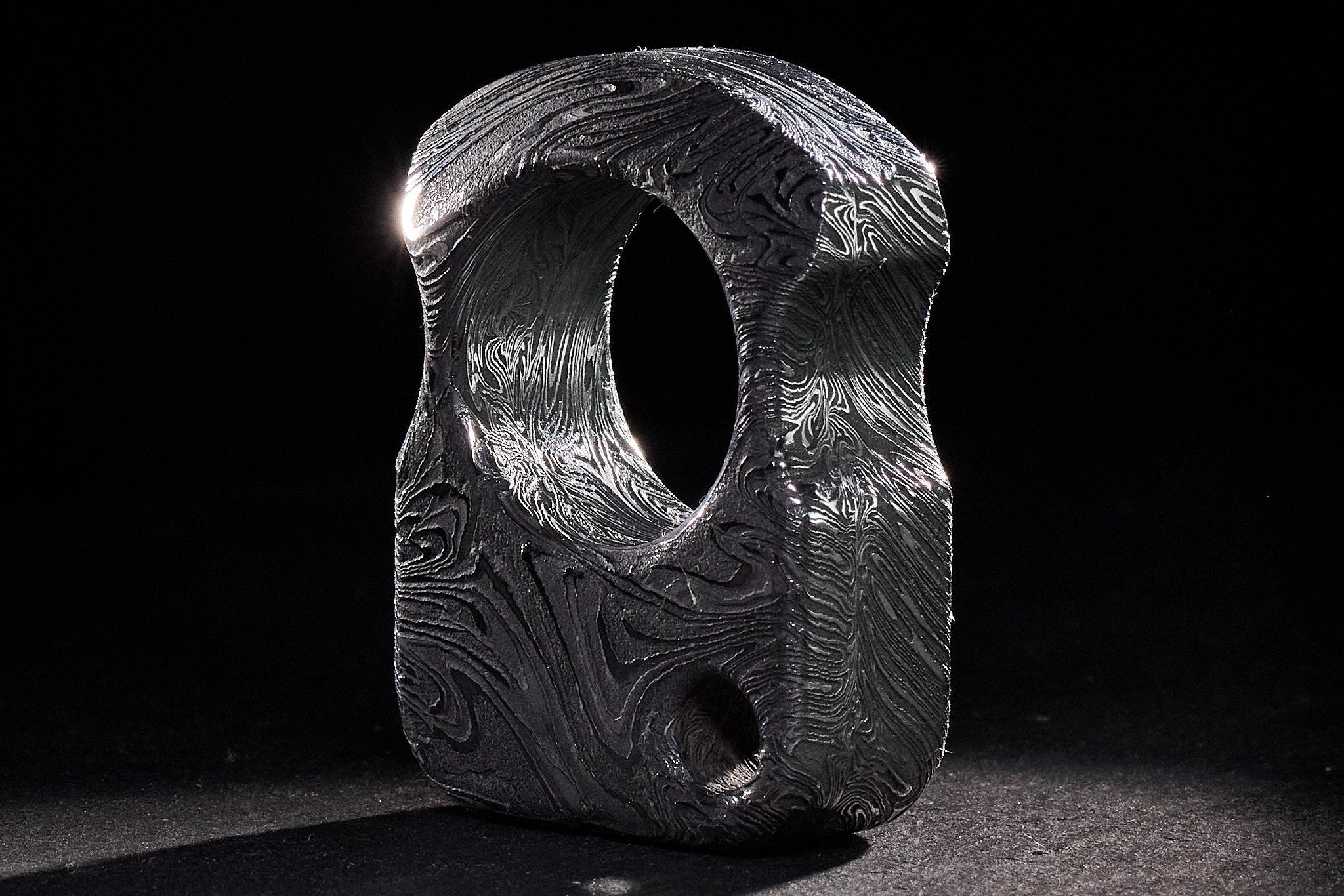 Hand-polished Sad Face brand hallmark on the surface of forged Damascus metal.