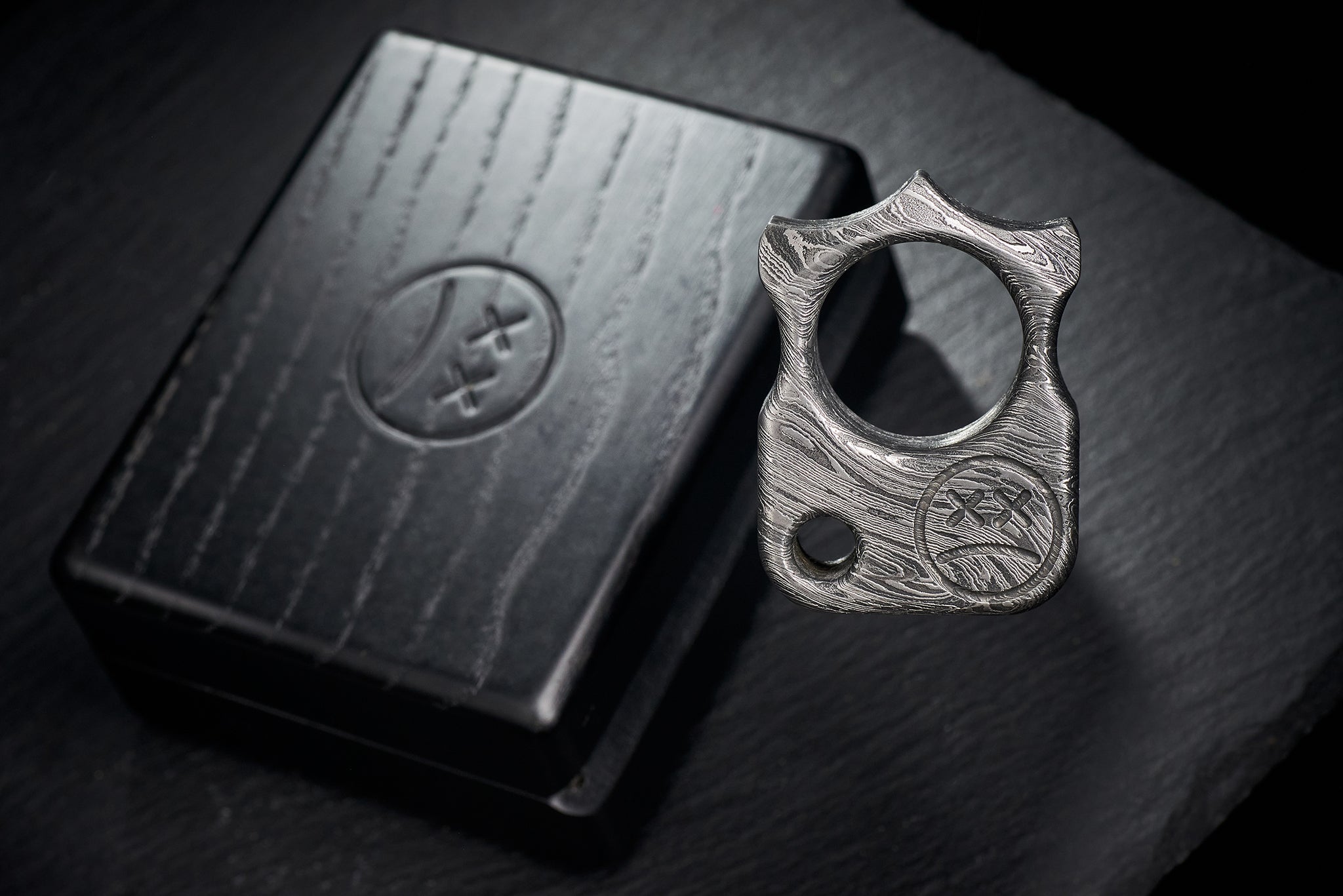 Close up of hand-etched Sad Face logo on high-contrast Damascus steel-1