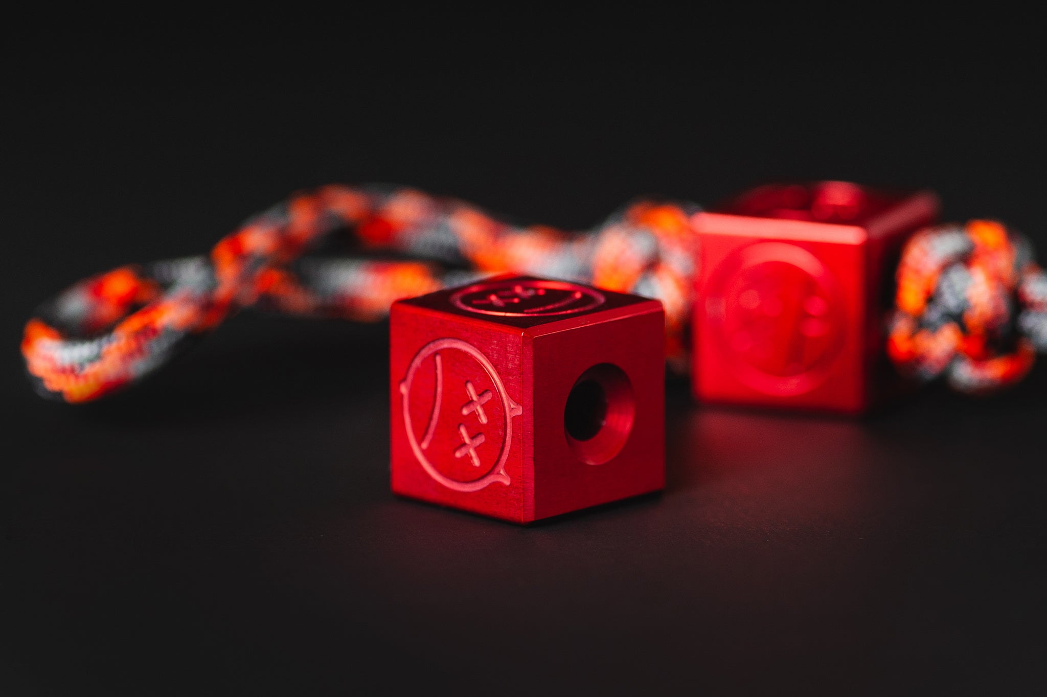 Red aluminum Sad Face bead showing the 6mm paracord channel.