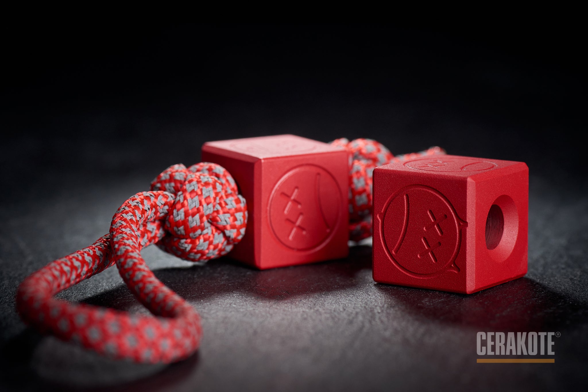 Ruby Red Cerakote Sad Face Cube bead on a lanyard.