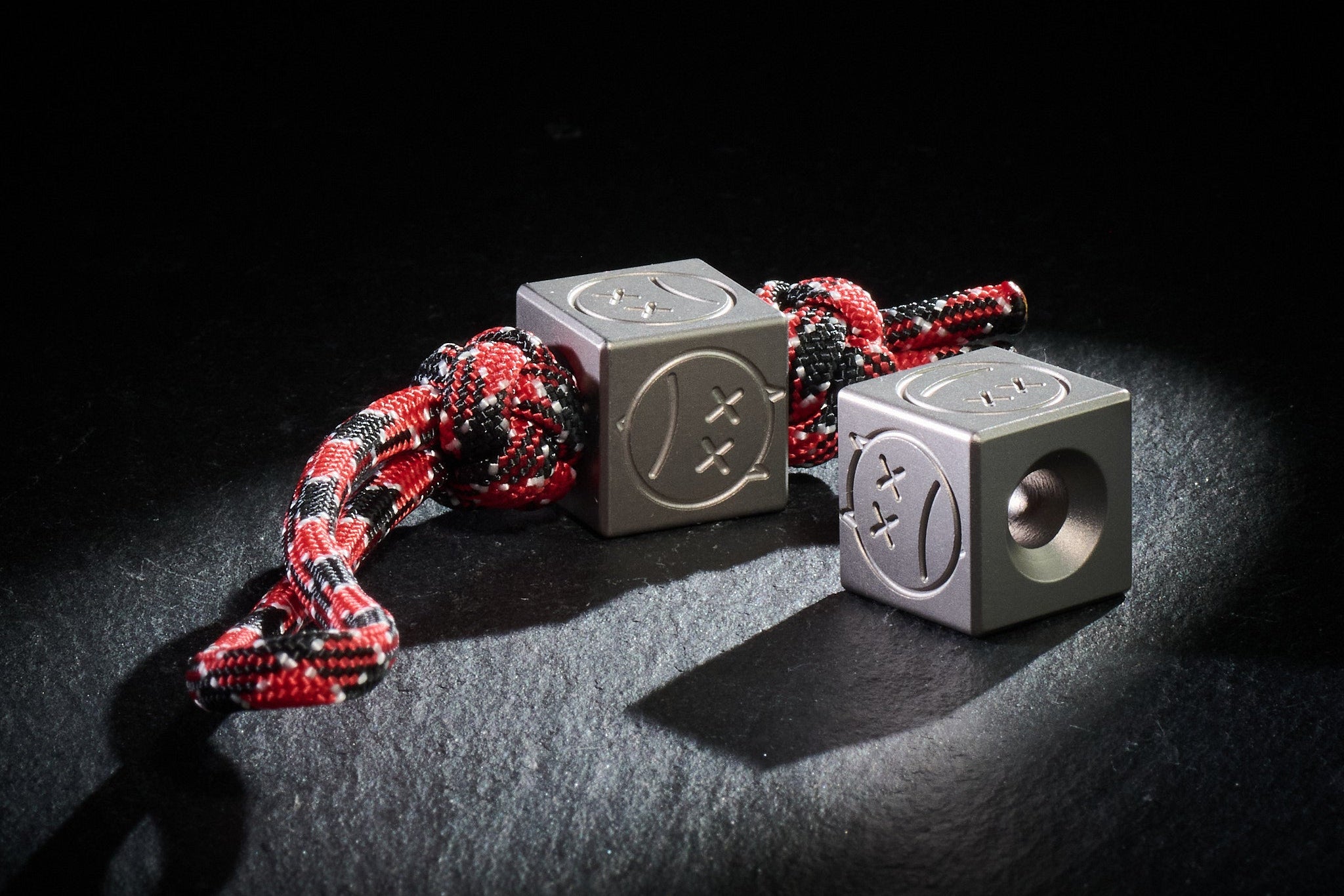 Sandblasted Titanium Sad Face Cube bead for knife lanyards.