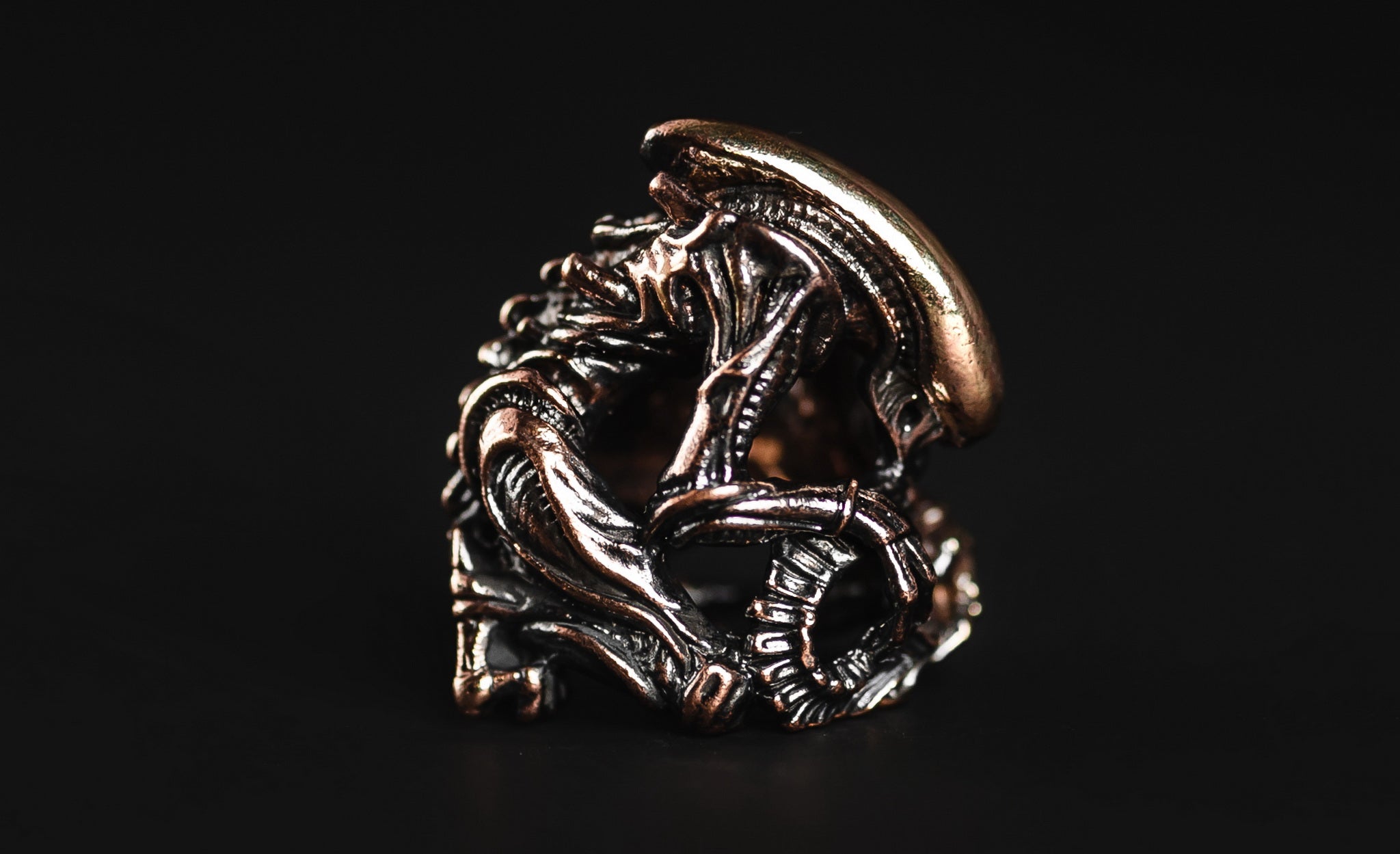 Profile view of the elongated Alien head brass bead showing the antique blackened finish.