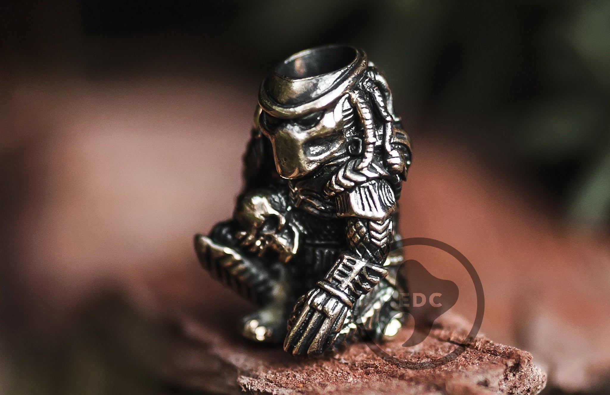 Solid brass Yautja Hunter Predator bead holding a human skull trophy.